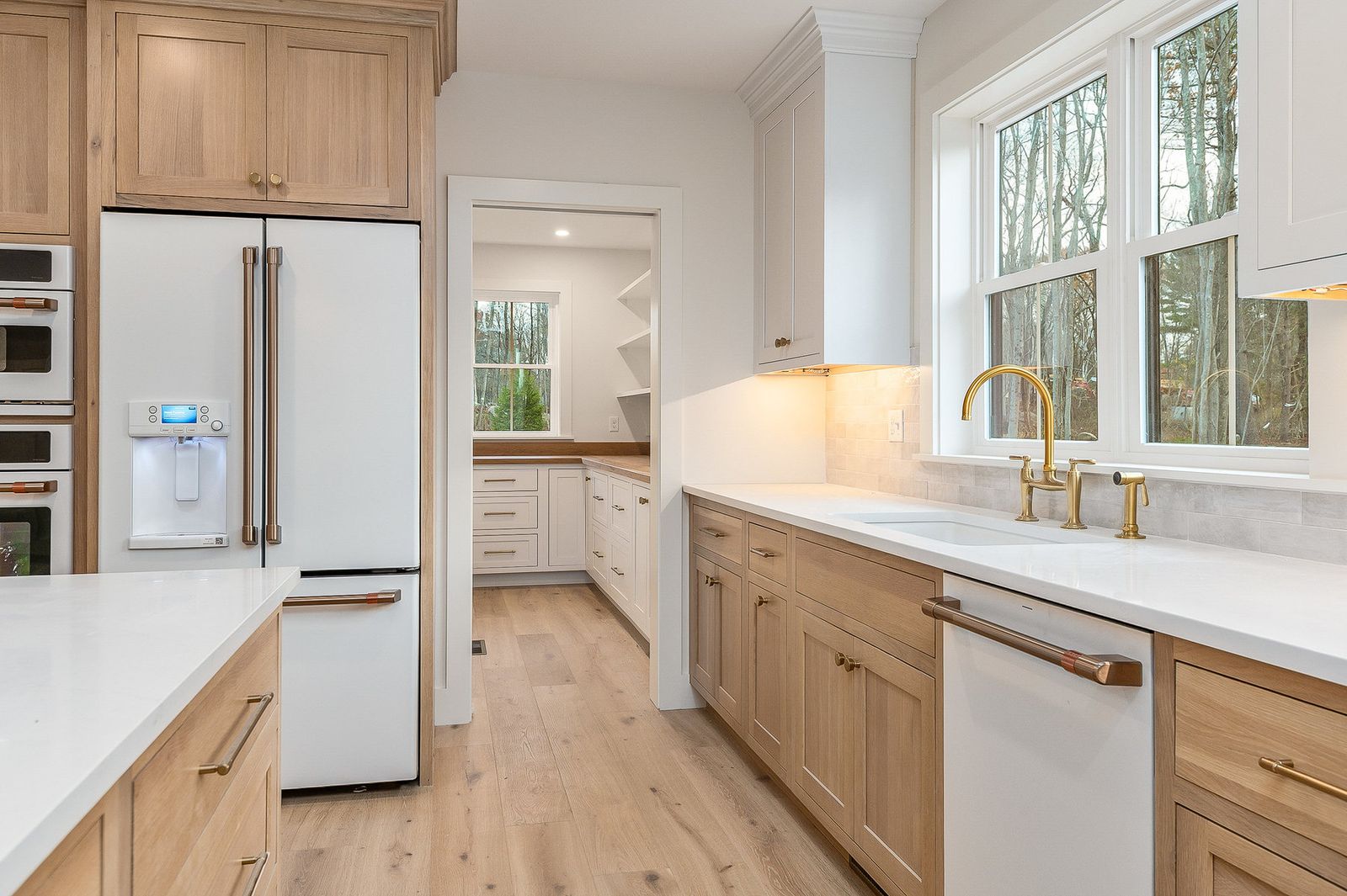Kitchen with quartz counters, a brass gooseneck faucet and a window above the sink - a River Birch Builders home in the New Hampshire Seacoast