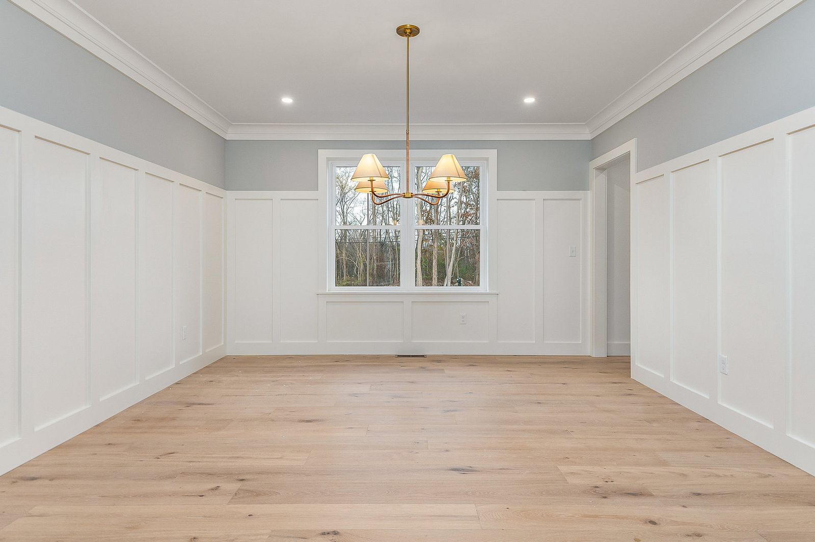 Dining room with board-and-batten wainscoting and a brass chandelier - a River Birch Builders home in the New Hampshire Seacoast