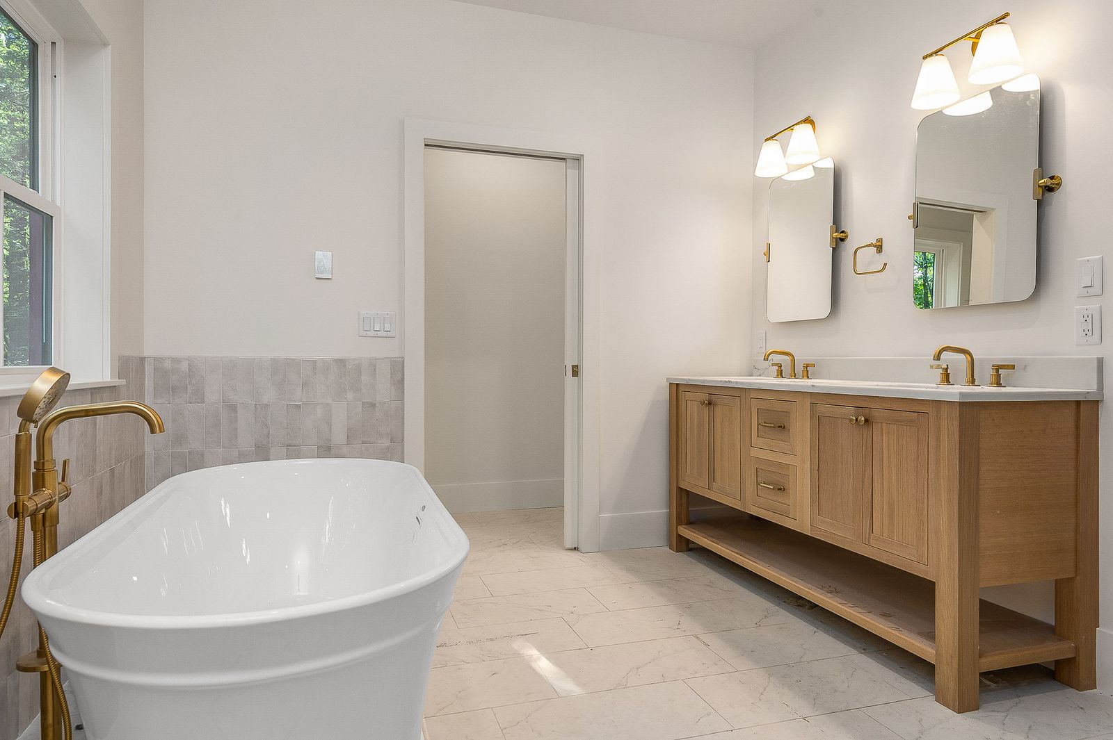 Bath with a freestanding tub, oak double vanity and brass sconces - a River Birch Builders home in the New Hampshire Seacoast