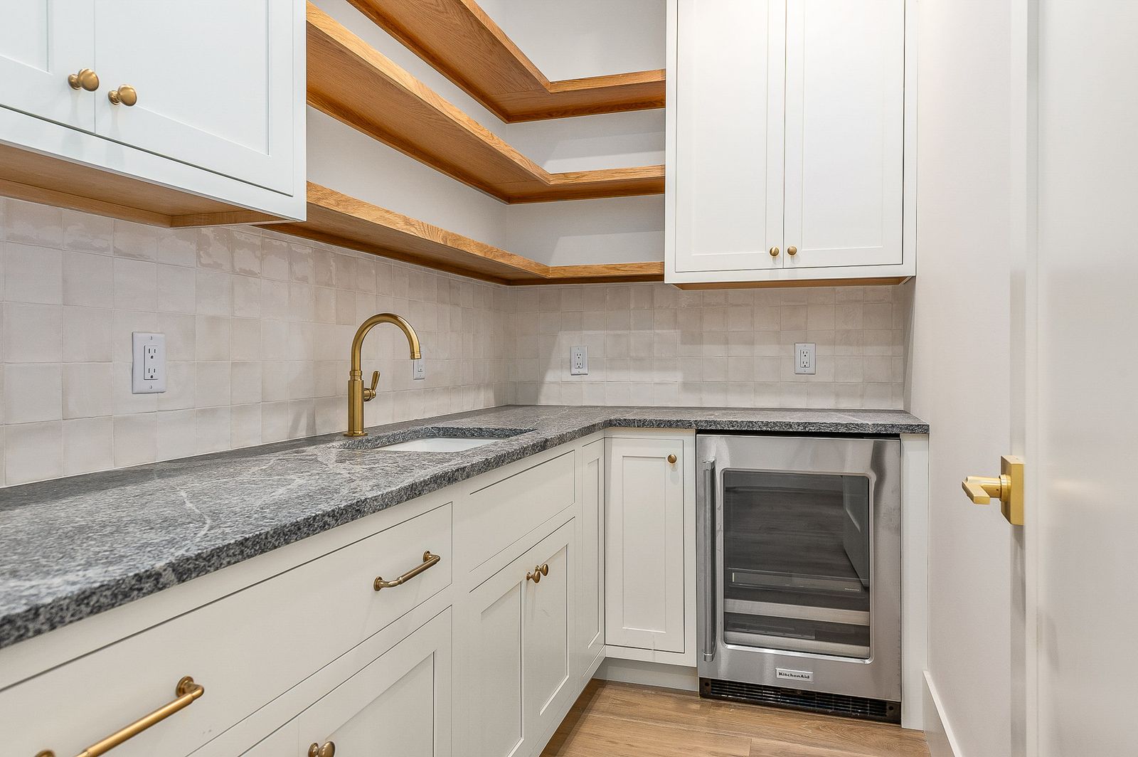 Butler pantry with stone counters, a beverage refrigerator and brass hardware - a River Birch Builders home in the New Hampshire Seacoast