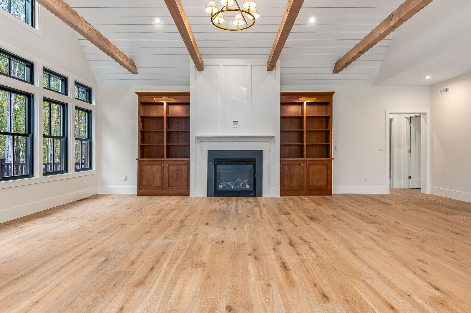 Living room with a beamed ceiling and a fireplace flanked by built-in shelving - a River Birch Builders home in the New Hampshire Seacoast